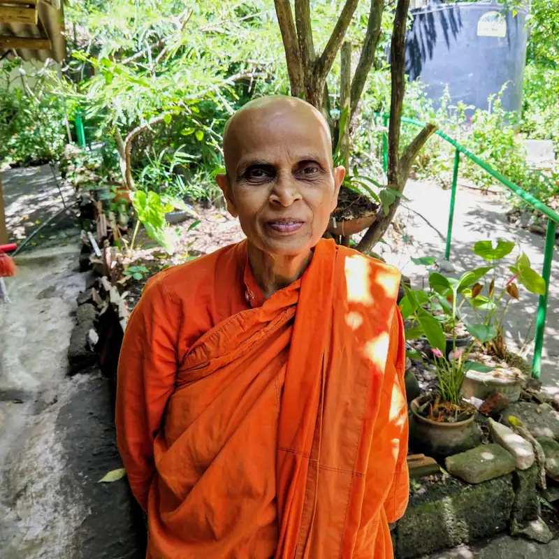 Venerable Kapilani Manio, smiling, in the garden of her nunnery in Sri Lanka.
